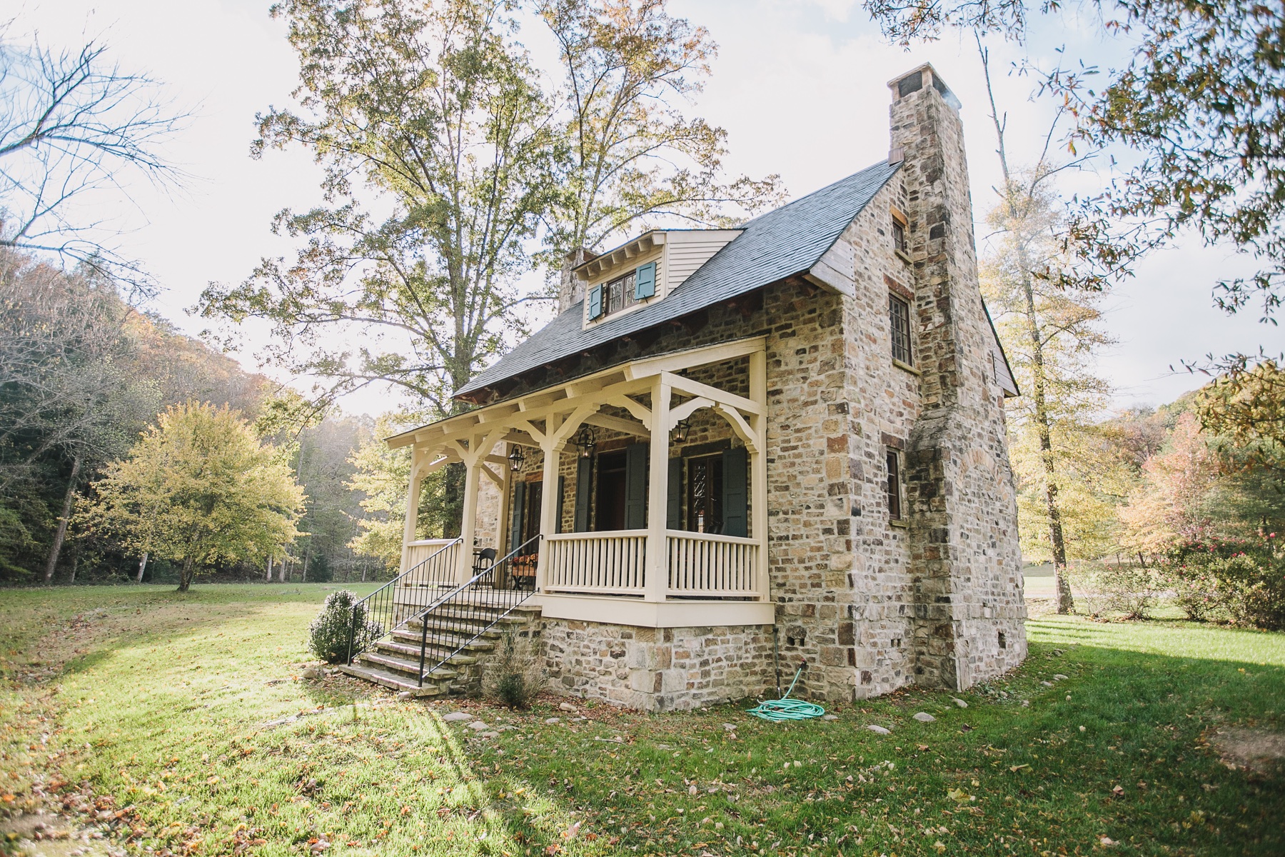 Stone cottage with a covered porch in an autumn landscape